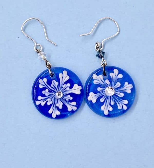 white snow flake 1" dangle earrings on a cobalt blue background with crystal bead accents