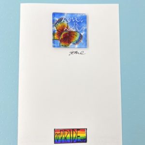 5x8 rainbow card with a 2x2 square rainbow butterfly glass piece affixed. The butterfly is positioned below the phrase "Love is Love" hand painted in white. The bottom center of the card front has a pride flag with the word Pride and 2020 and a heart.