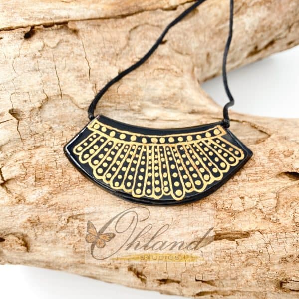 A necklace which is inspired by Ruth Bader Ginsberg's dissent collar on a driftwood background