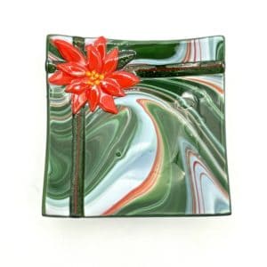 square glass bowl with red green and white swirled glass. Bowl looks like a gift with shiny green glass ribbon and a poinsettia flower accented in 24 carat gold in one corner