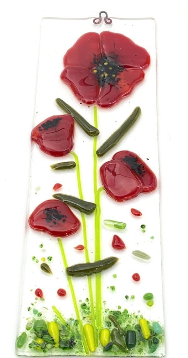 four red poppies with small red bits on a sun catcher