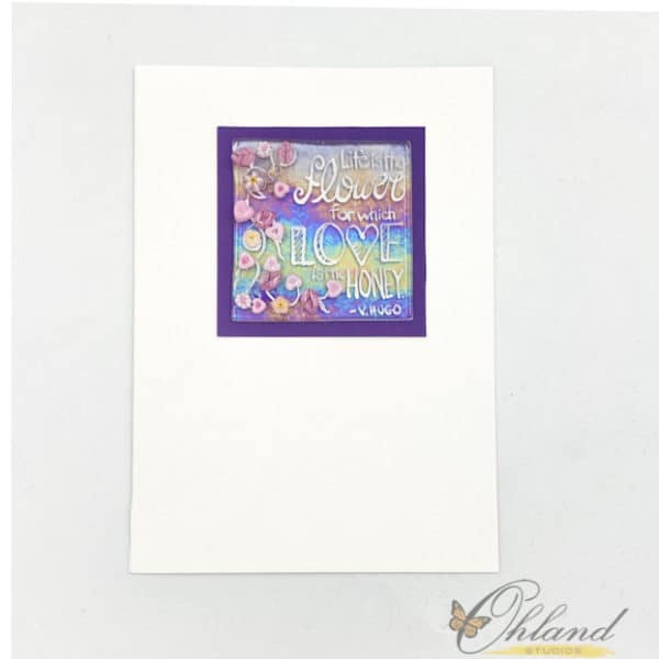 Irridescent glass square with pink and purple flowers mounted on a dark purple background that says "Life is the flower for which LOVE is the HONEY" - V. Hugo in hand penned enamel