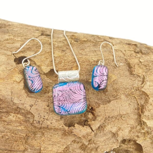 jewelry set of pendant and earrings, teal background glass with pink swirly very shiny design on top, earrings have sterling silver French ear wires